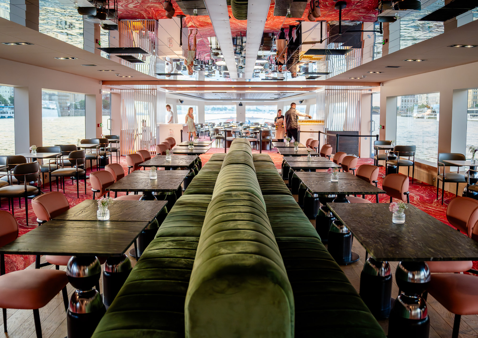 Panoramic indoor lounge with comfortable table seating aboard a Bud By Boat cruise.