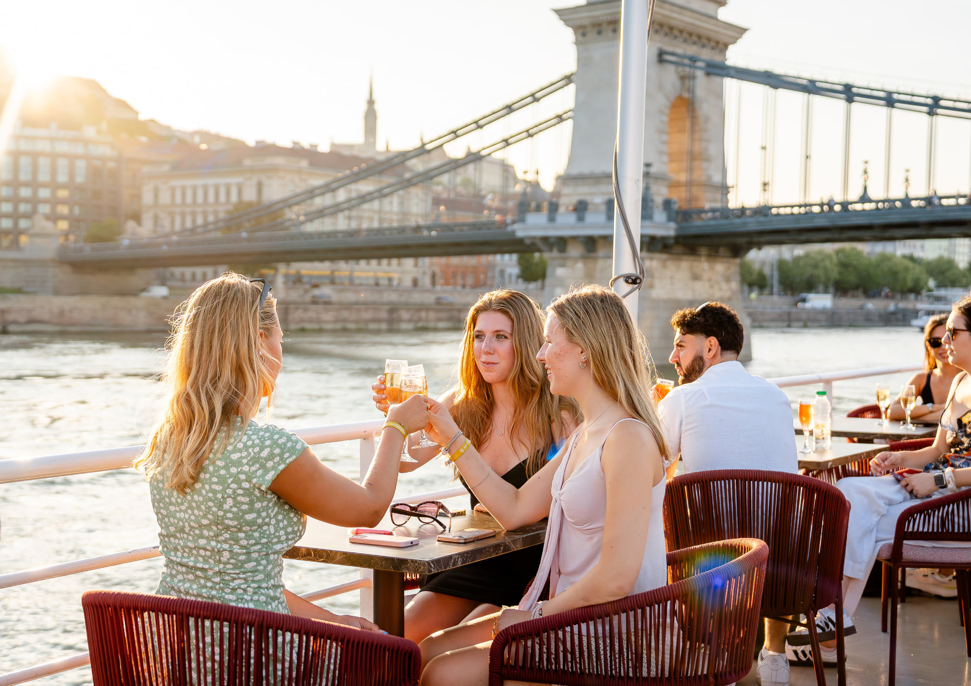 Guests toasting with prosecco on the open deck of a Bud By Boat cruise near Chain Bridge.