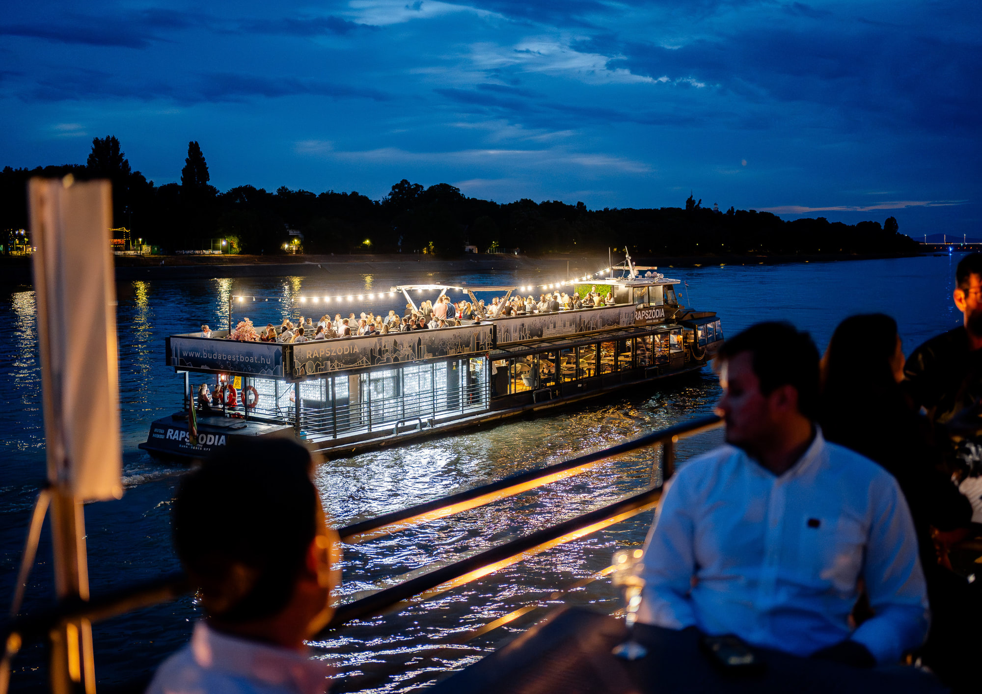 Rapszódia cruise boat carrying Bud By Boat guests on the Danube at night.